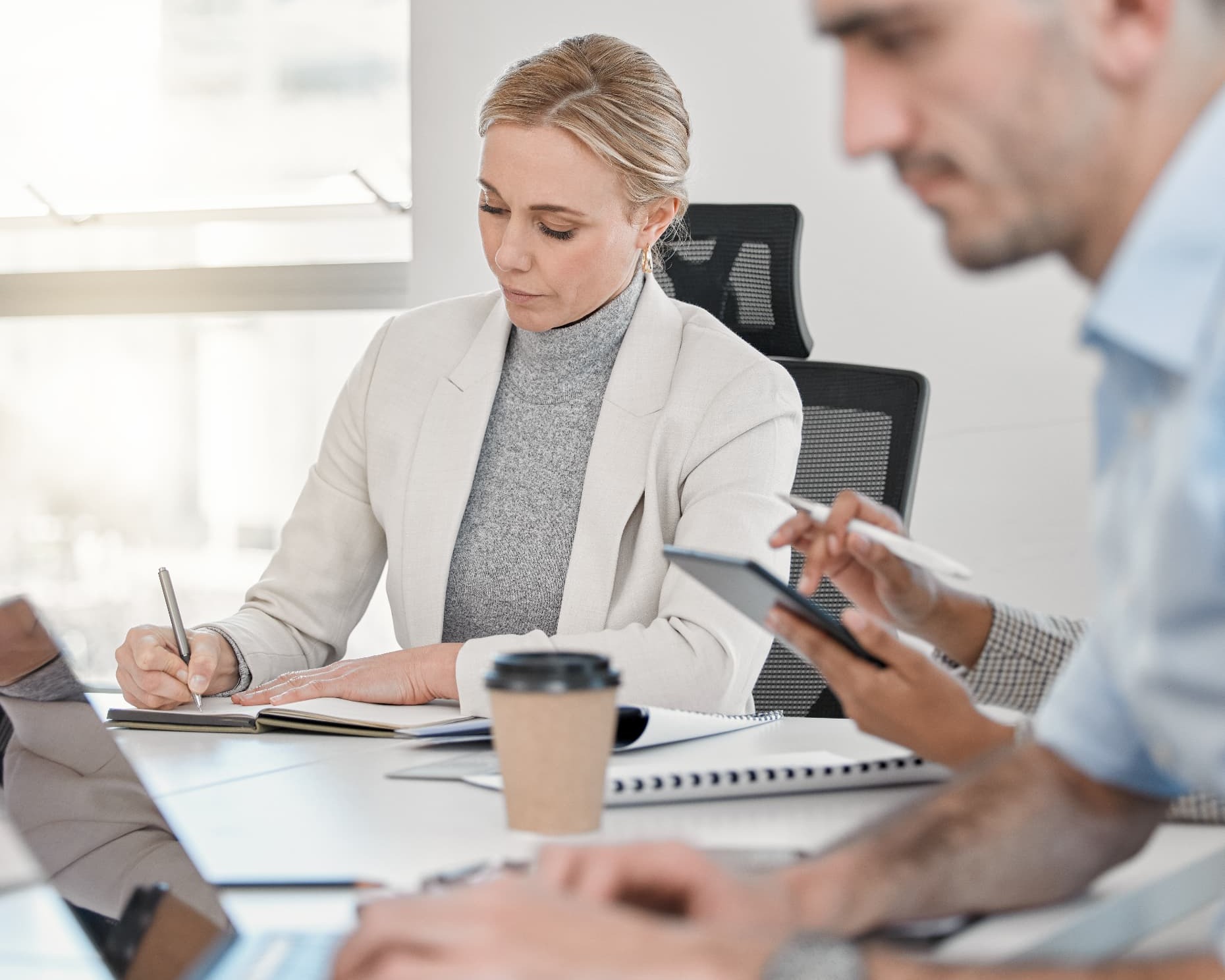 Woman writing in a notebook during a focused business session